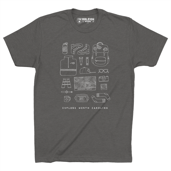 Heavy metal colored t-shirt with different hiking accessories such as boots, backpack, topo map, binoculars, sunglasses and more, sketched in white.  Bottom of the shirt says Explore North Carolina. 