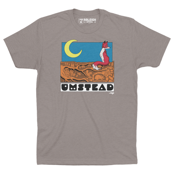 Stone gray colored t-shirt with a fox sitting under a crescent moon on tree roots and the word Umstead in black letters under design.