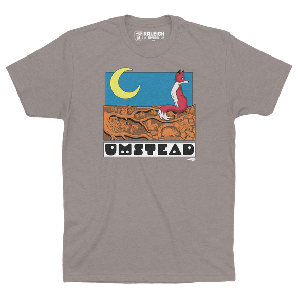 Stone gray colored t-shirt with a fox sitting under a crescent moon on tree roots and the word Umstead in black letters under design.